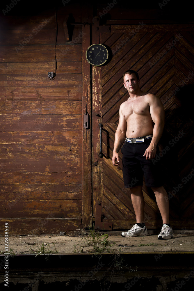 muscular man with clock on the wooden background