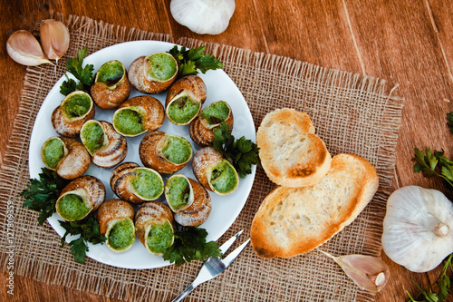 Escargots de Bourgogne - Snails with herbs butter, gourmet dish in French traditional  with parsley and bread on white platter photo