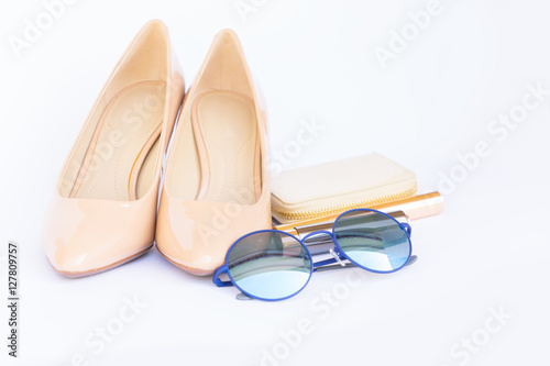 Nude colored high heels still life with wallet, sun glasses on white background