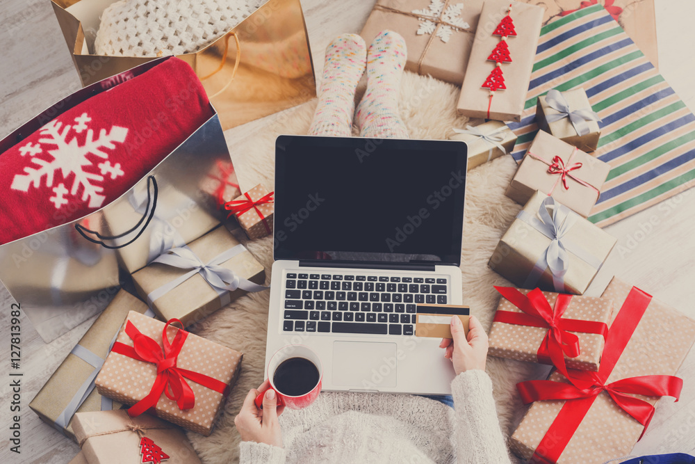 Fototapeta premium Woman makes christmas shopping online with laptop, above view