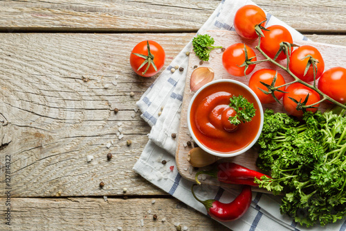 Ketchup and ingredients on wood background