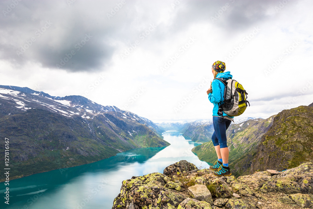 Obraz premium Young woman hiking on Besseggen. Happy girl enjoy beautiful lake and good weather in Norway.