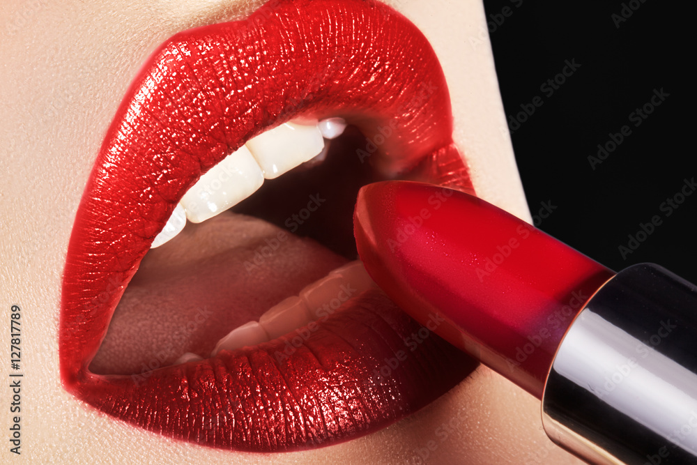 Obraz premium Close-up of woman's lips with fashion red make-up. Beautiful female mouth, full lips with perfect makeup. Part of female face. Macro shot of beautiful make up on full lips. Choice lipstick