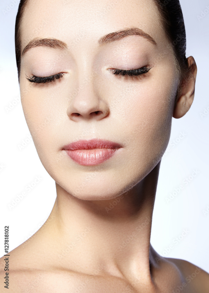 Fototapeta premium Beautiful model with natural fashion make-up. Close-up portrait sexy woman with glamour lip gloss makeup and long eyelashes. Celebrate visage, clean skin, eyebrows, lashes. Beautiful Smile