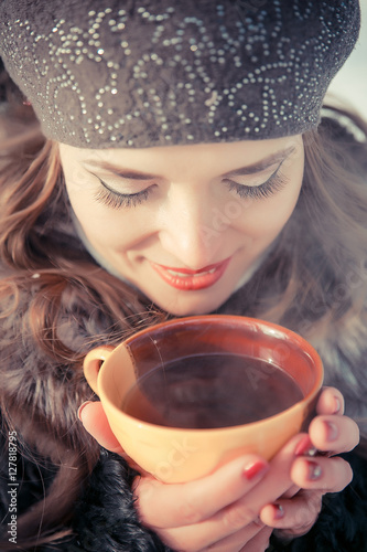 Young woman holding cup with tea outdoors in winter