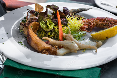 Verschiedene gegrillte Fischsorten auf einem weißen Teller photo