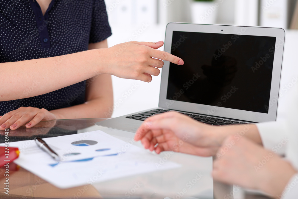 Group of business people at meeting discussing financial results. Women pointing into laptop computer monitor Group of business people at meeting discussing financial results. Women pointing into laptop computer monitor