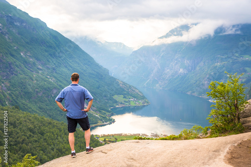 Young men relax on Geiranger fjord. Happy friends enjoy beautiful lake and good weather in Norway.