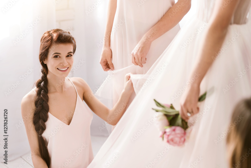 Smiling young bridesmaid helping the bride to get ready Smiling young bridesmaid helping the bride to get ready