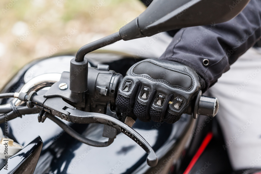 Obraz premium Biker sitting on motorcycle, close-up view on hands on handlebar