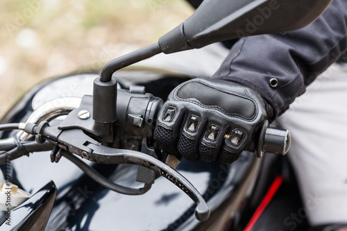 Biker sitting on motorcycle, close-up view on hands on handlebar © Alex Ishchenko