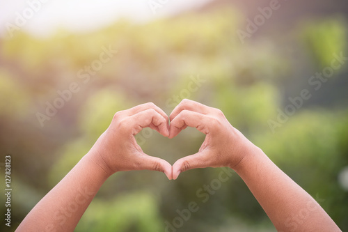 Hands with heart sign on green blur at garden. Love concept © SKT Studio