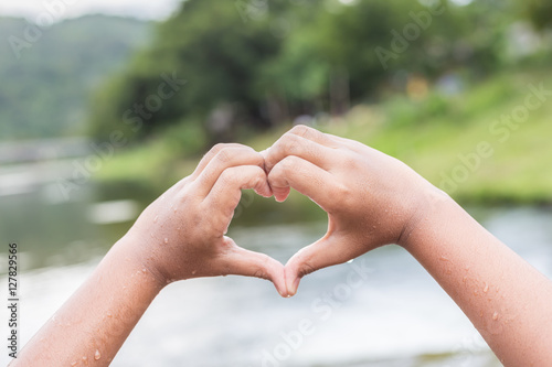 Wet hands with heart sign at the river in Thailand