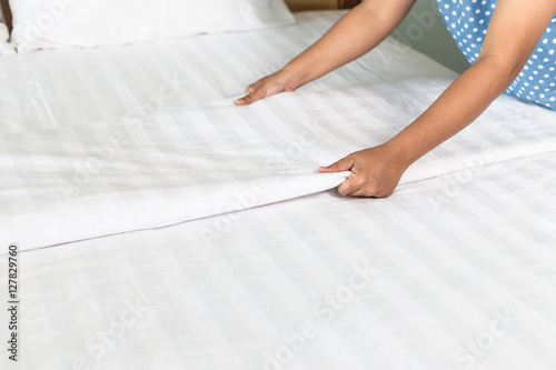 Hand set up white bed sheet in hotel room
