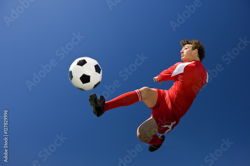 Footballer kicks ball.