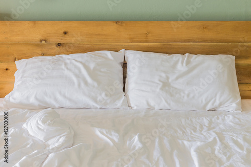 Fototapeta Naklejka Na Ścianę i Meble -  White bedding sheets and pillow on wooden wall room background,