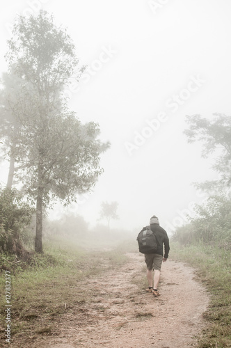 Young man walking in the fog on the mountain