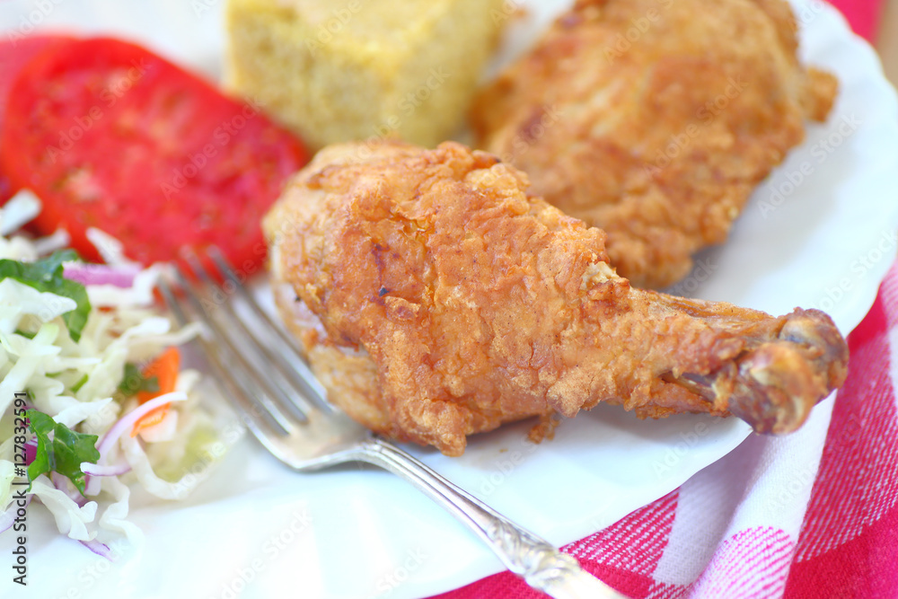 Fried chicken with coleslaw and cornbread with fork