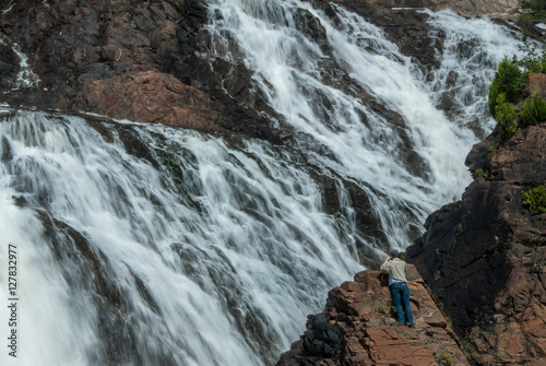 large waterfall with tourist taking photo from rockface