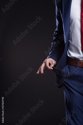 Businessman pulling out his empty pocket against a black background