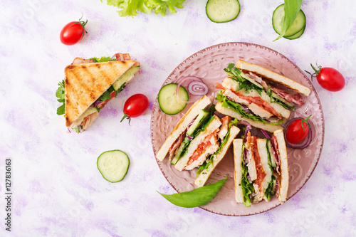 Club sandwich with chicken breast, bacon, tomato, cucumber and herbs. Top view
