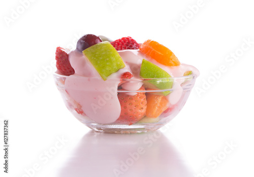 Nutritiousbreakfast with fruit salad topped with pink strawberry yogurt in a glass bowl, on white background photo