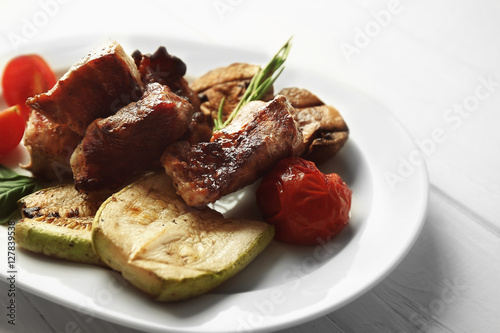 Grilled meat with vegetables on plate, closeup
