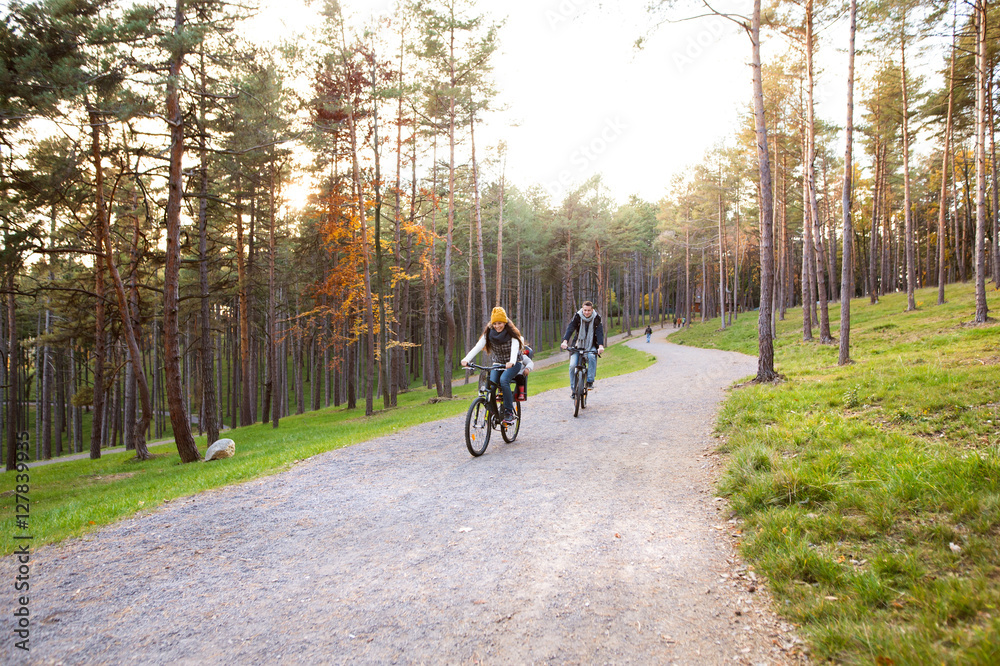 Young family in warm clothes cycling in autumn park