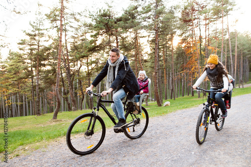 Young family in warm clothes cycling in autumn park