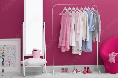 Fashionable clothes hanging on rack at modern dressing room © Africa Studio