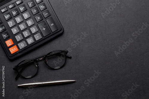 Office desk table with calculator, pen and glasses
