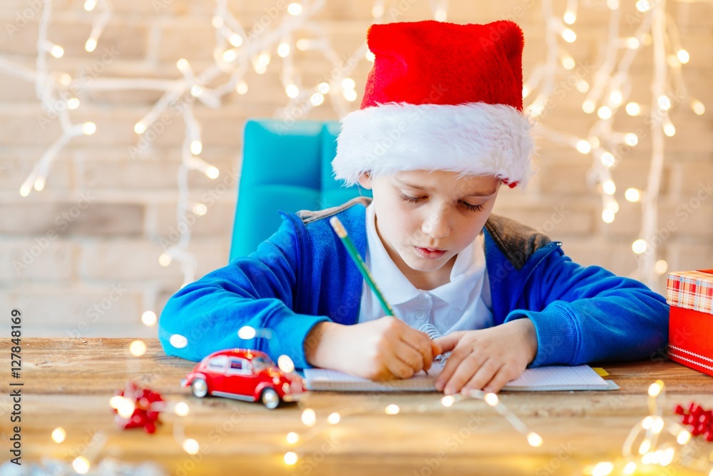 Child writing a letter to Santa Claus at home.