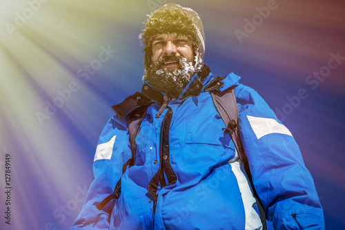 Young man with snowy beard on the top of mountain