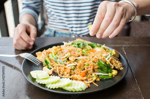 Female hand squeezing lime on Pad Thai