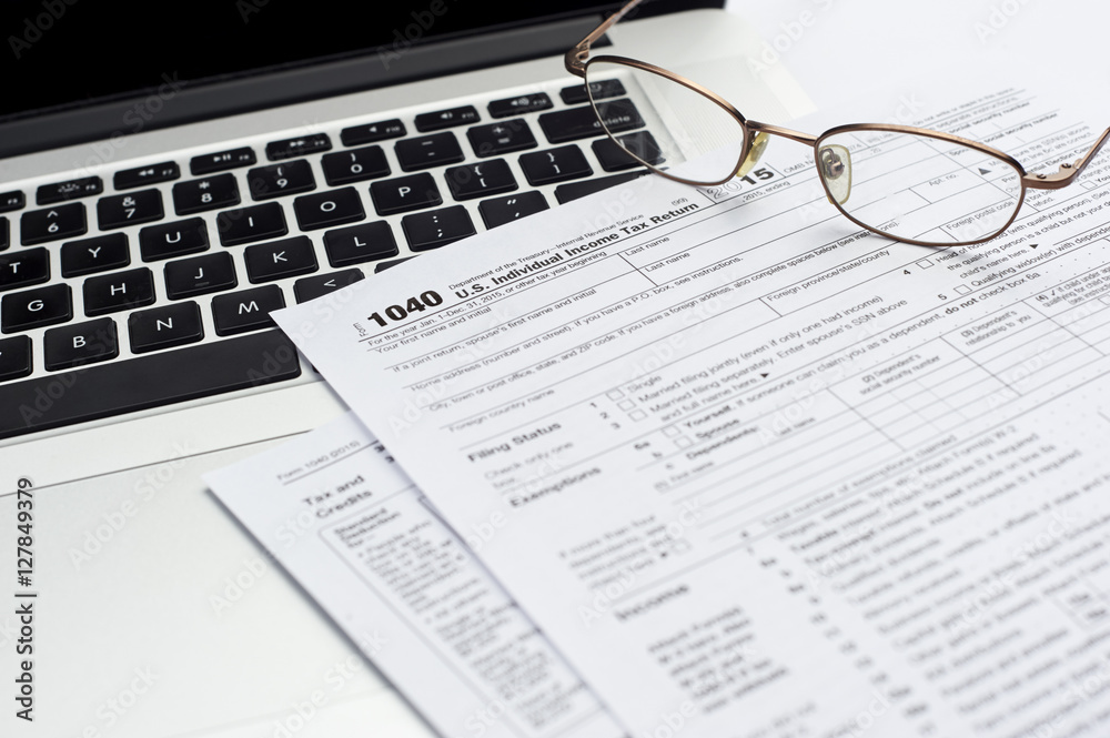 Obraz premium U.S. 1040 income tax return form with laptop and glasses