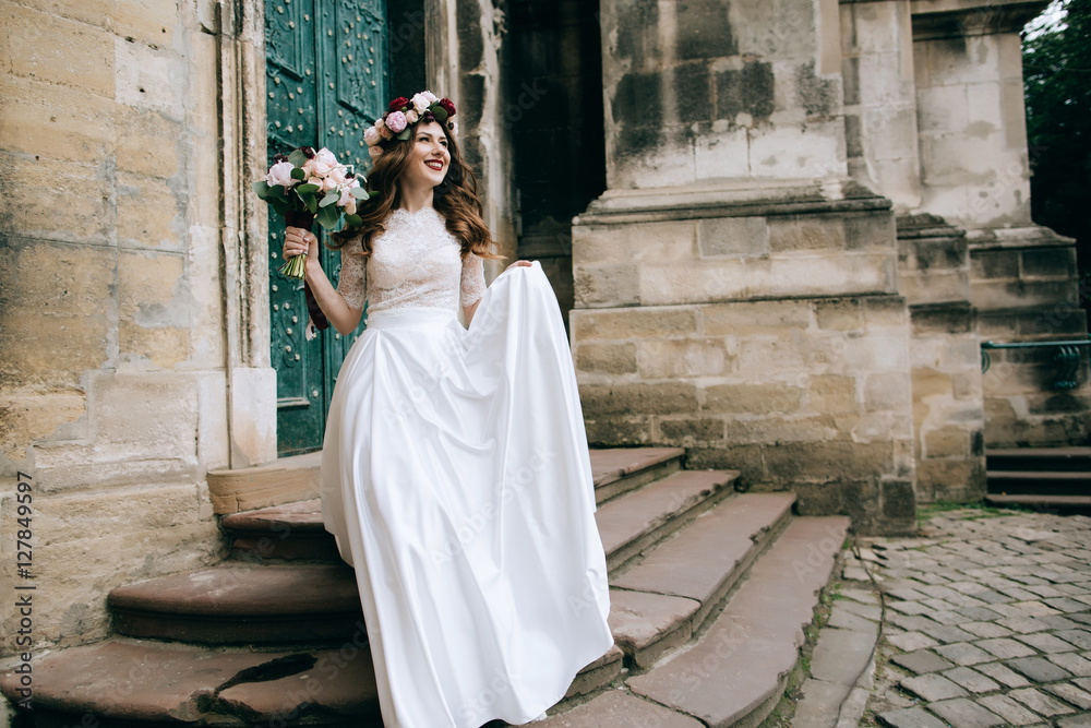 Beautiful bride portrait outdoors on the steps of the church in old city. Wedding concept