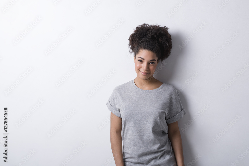 Girl wearing gray t-shirt, standing near a white wall Girl wearing gray t-shirt, standing near a white wall