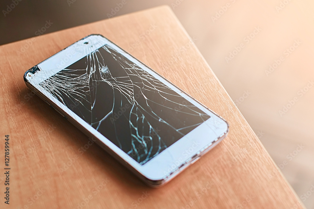 Smartphone with broken screen on the wooden table