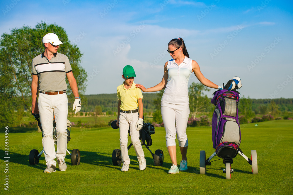 Family golfers walking on golf course at sunny day Family golfers walking on golf course at sunny day