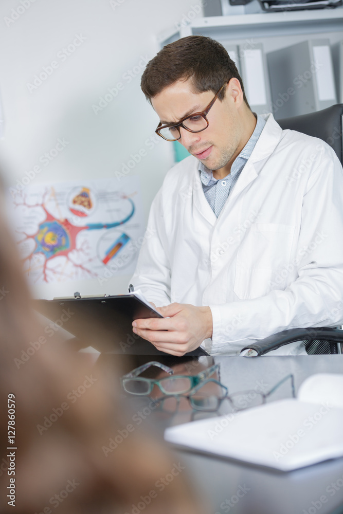 ophthalmologist in exam room writing on clipboard