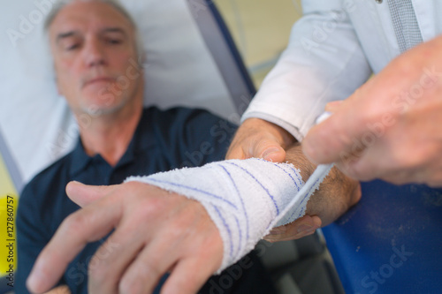 doctor bandaging his patient hand in medical office