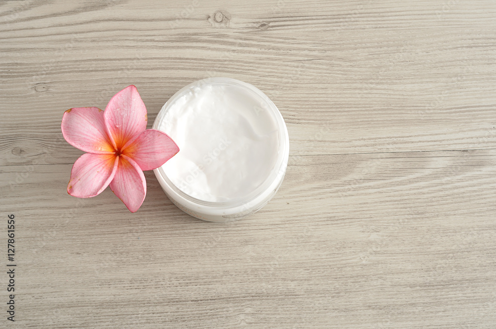 Body lotion in a container with a pink frangipani flower Body lotion in a container with a pink frangipani flower