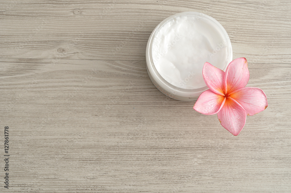 Body lotion in a container with a pink frangipani flower Body lotion in a container with a pink frangipani flower