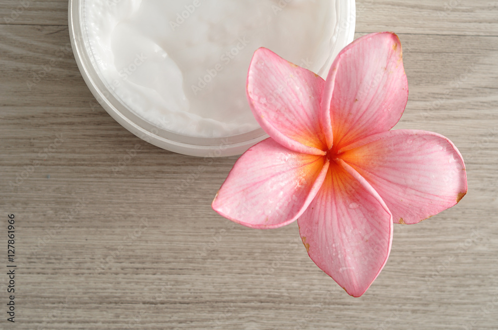 Body lotion in a container with a pink frangipani flower Body lotion in a container with a pink frangipani flower