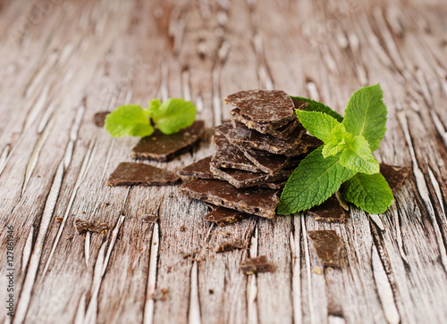 pieces of chocolate with mint on wooden background, selective focus