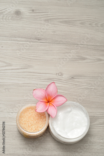 Body lotion and bath salt displayed with a frangipani flower