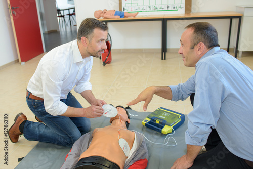 Men training to use defibrillator photo