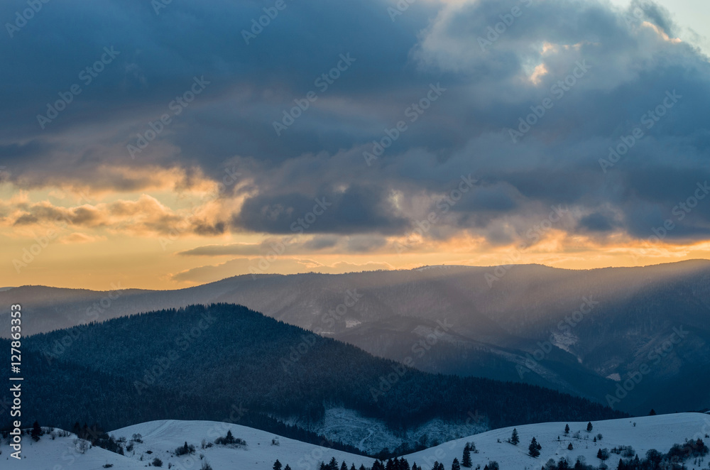 Winter sunset in the mountains. Multi-colored clouds, illuminated by the sun.