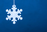 Cute white safety reflector in the form of snowflakes on blue background. Necessary equipment to pedestrians for walks during dark conditions.