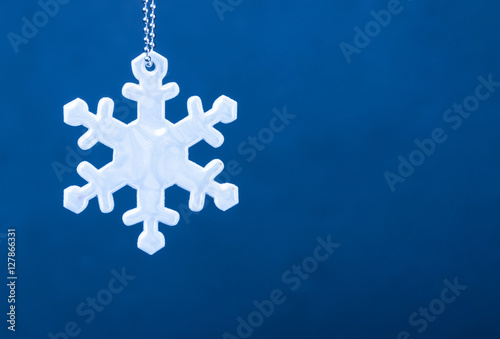 Cute white safety reflector in the form of snowflakes on blue background. Necessary equipment to pedestrians for walks during dark conditions. photo